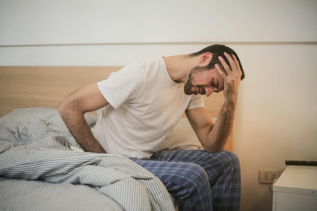 Young Man in Sleepwear Suffering From Headache