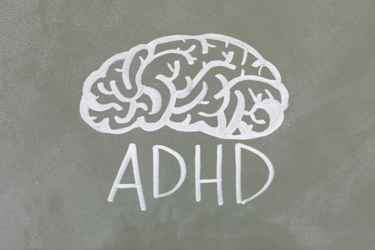 The letters ‘ADHD’ in all uppercase form written in white under a brain drawn in white